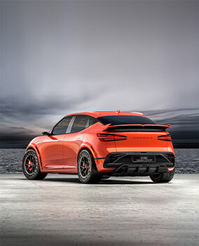 The GV60 Magma Concept vehicle is stationary on a flat surface with the horizon in the background, rear view. The car features an orange-hued body that harmonizes with red rear lights. The Genesis logo is positioned between the rear lights.